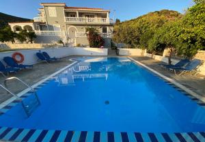 a large blue swimming pool with chairs and a house at Villa Karras in Pythagoreio
