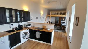 a kitchen with a washer and dryer in a room at The Uyeasound Old Pier Cottage in Belmont