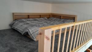 a bed in a bedroom next to a wooden rail at The Uyeasound Old Pier Cottage in Belmont