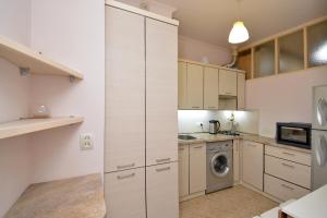 a kitchen with white cabinets and a washer and dryer at The Best Apartment in Yerevan