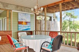 a porch with a table and chairs and a chandelier at Rehoboth Cottage by Pristine Properties Vacation Rentals in Indian Pass
