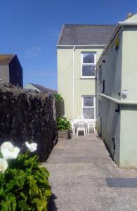 a patio with two white chairs and a house at large 4 bedroom in Pembroke Dock