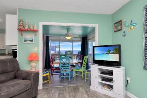 a living room with a television and a table with chairs at Sea Shell by Pristine Properties Vacation Rentals in Mexico Beach