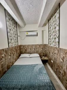 a small bedroom with a bed and two windows at LUA origenes Alojamiento FIRST FLOOR in Santa Marta