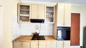 a kitchen with white cabinets and a black stove at Phumula Home in Mbabane