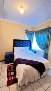 a bedroom with a large bed with blue curtains at Phumula Home in Mbabane