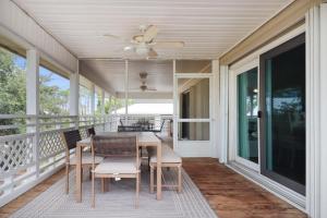 a screened porch with a table and chairs and a ceiling fan at Woofs and Waves by Pristine Properties Vacation Rentals in Cape San Blas