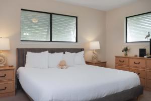 a bedroom with a white bed with a teddy bear on it at Woofs and Waves by Pristine Properties Vacation Rentals in Cape San Blas +74 photos