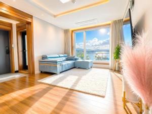 a living room with a blue couch and a large window at Chuncheon Kerensia Pension in Chuncheon