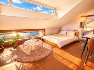 a bedroom with a bed and a table and a window at Chuncheon Kerensia Pension in Chuncheon