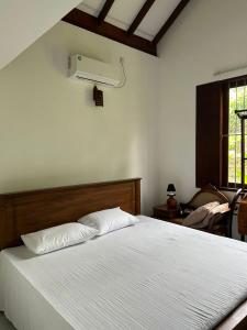 a bedroom with a white bed and a fan at Induruwa Cottage in Induruwa
