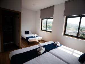 two beds in a room with two windows at Bahía de San Simón in Redondela