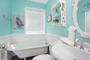 a bathroom with blue walls and a white tub and a sink at Narrow Escape by Pristine Properties Vacation Rentals in Cape San Blas +28 photos