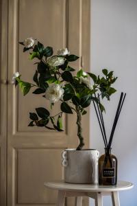 a vase with white flowers on a table next to a door at Rooms Buonanotte Barbarossa in Prato
