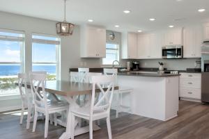 a kitchen with white cabinets and a table and chairs at Pelican Roost A by Pristine Properties Vacation Rentals in Mexico Beach