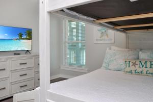 a white bedroom with a bed and a television at Pelican Roost A by Pristine Properties Vacation Rentals in Mexico Beach