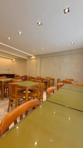 an empty classroom with green tables and wooden chairs at Hotel Pousada Arco Íris Manaira in João Pessoa