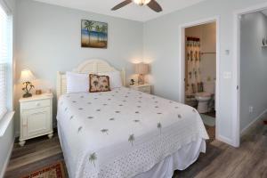 a bedroom with a white bed and a bathroom at Sandcastle C by Pristine Properties Vacation Rentals in Mexico Beach