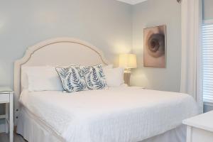 a white bedroom with a white bed with a white headboard at Summerhouse 309 by Pristine Properties in Mexico Beach