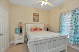 a bedroom with a white bed and a ceiling fan at Summerhouse 203 by Pristine Properties Vacation Rentals in Mexico Beach +30 photos