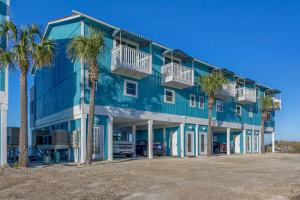 a blue building with palm trees in front of it at Their Inheritance by Pristine Properties Vacation Rentals in Indian Pass