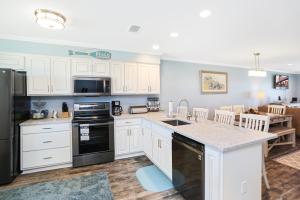 a kitchen with white cabinets and a black appliances at Beach Therapy by Pristine Properties Vacation Rentals in Cape San Blas