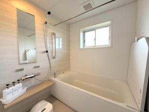 a bathroom with a tub and a toilet and a window at Ango KIKAIJIMA in Onozu +41 photos