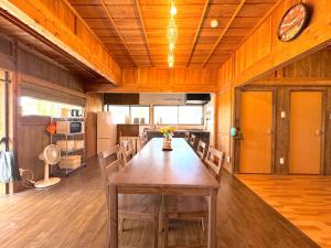 a dining room with a large wooden table and chairs at Ango KIKAIJIMA in Onozu