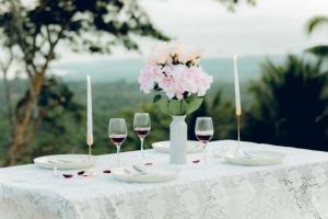 a table with wine glasses and a vase of flowers at Romantic A-Frame Cabin w/ a View + WiFi in Samal