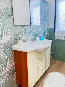 a bathroom with a sink and a palm leaf wallpaper at Chalet del girasole in Castellabate +44 photos