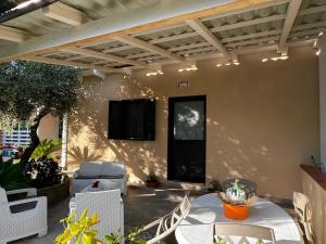a patio with a table and chairs and a television on a wall at Chalet del girasole in Castellabate