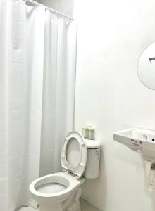 a white bathroom with a toilet and a sink at Balay by JMB in Legazpi