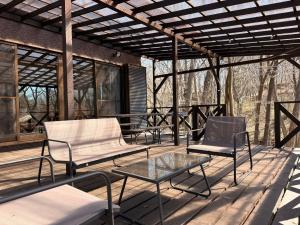 a patio with two chairs and a glass table at BBQ屋根付き大型ウッドデッキ川のせせらぎを聴きながら贅沢時間ペット同伴OK森と音に癒されるコテージ Rill in Nasu