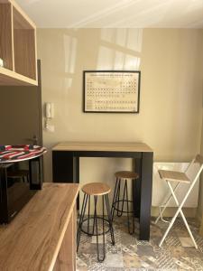 a kitchen with a bar with stools and a score on the wall at Studio charmant avec terrasse privée in Oradour-sur-Glane