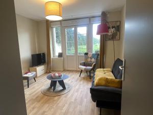 a living room with a couch and a table at Studio charmant avec terrasse privée in Oradour-sur-Glane