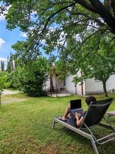 a boy sitting in a lawn chair with a laptop at Pavle Petra apartments in Mitrovići