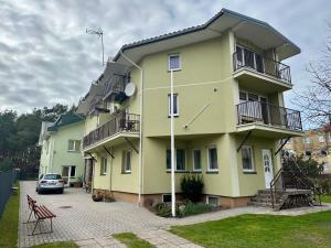 a yellow building with a car parked in front of it at Pas Aldoną in Šventoji