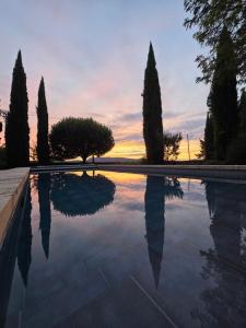 a swimming pool with trees and a sunset in the background at La Maison de Piolon in Beaumont-du-Ventoux