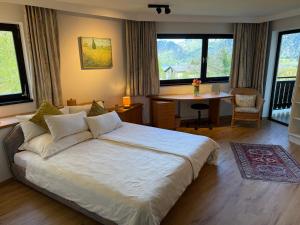 a bedroom with a bed and a desk and windows at Die Landhausvilla in Unterach am Attersee in Unterach am Attersee
