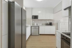 a kitchen with white cabinets and a stainless steel refrigerator at Coastal Condo Strand in Strand