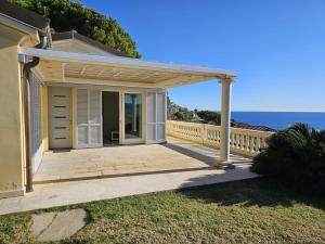 a house with a wooden porch with the ocean in the background at Mare e Relax - La Villetta ai Tre Ponti - Trilocale in Sanremo