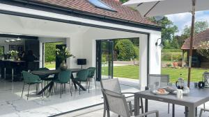 a patio with a table and chairs and a dining room at Luxury Ascot Villa Steps from Royal Ascot, 5 mins to Legoland Windsor Resort, 10 mins to Windsor Castle in Ascot