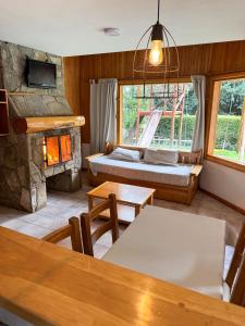 a living room with a stone fireplace and a table at Apart Hotel del Pellin in San Martín de los Andes