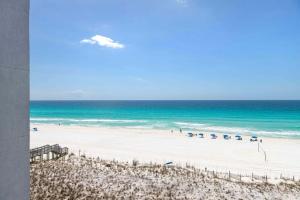 a beach with many umbrellas and the ocean at Spacious gulf front condo with beach access in Fort Walton Beach