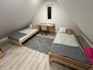 a attic room with two beds and a table at Na domek do Pati in Przejma Wielka