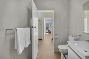 a white bathroom with a toilet and a sink at Coastal Condo Strand in Strand +40 photos