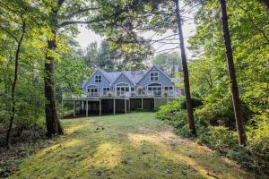 a large blue house in the woods with a yard at Bufflehead Hideaway in Kennebunk