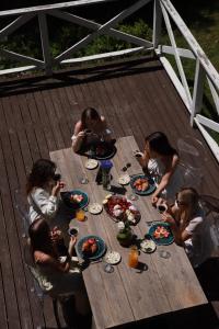 a group of people sitting around a wooden table eating food at Маєток Ліс і Гори in Bukovel