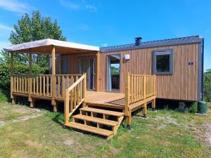 a large wooden cabin with a porch and a deck at Camping de la Tour AMBON in Ambon