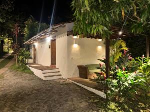 a small house with a bench in a yard at night at Costeño River Minca in Minca